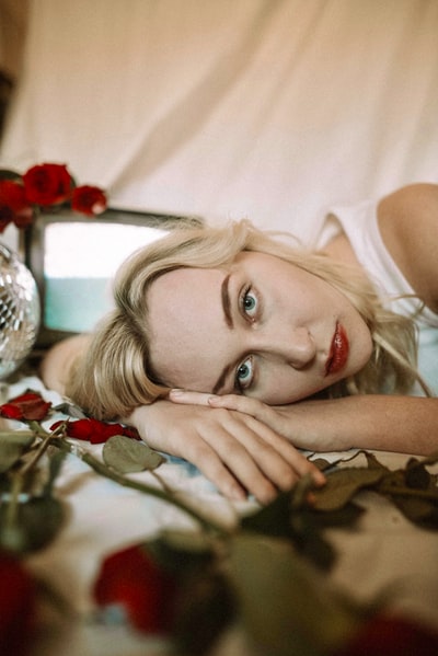 The girl wearing a white vest lying on the bed
